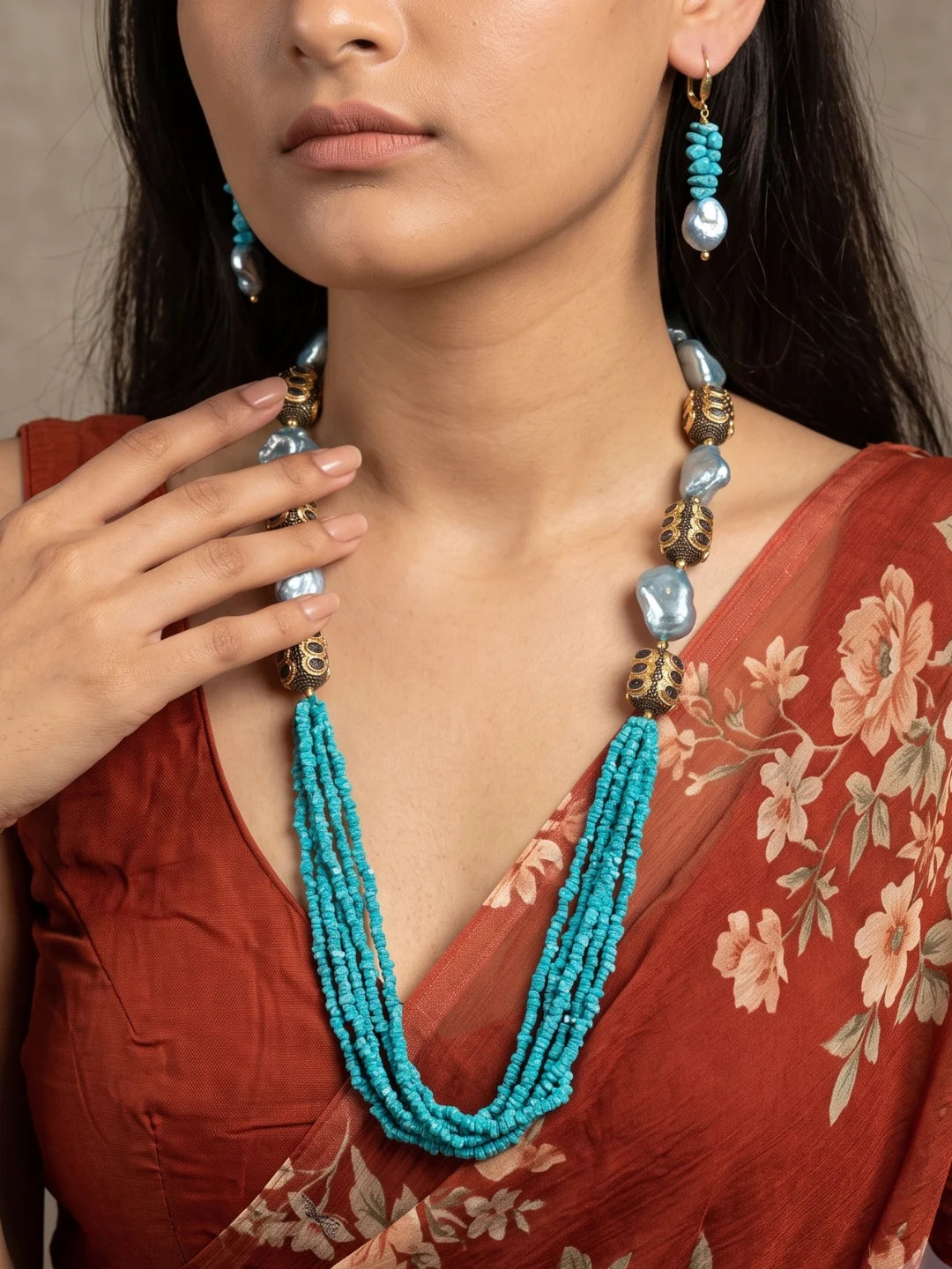 Full view of a layered turquoise blue necklace with chip beads, aqua-blue shell pearls and gold-toned accent beads, shown with matching drop earrings