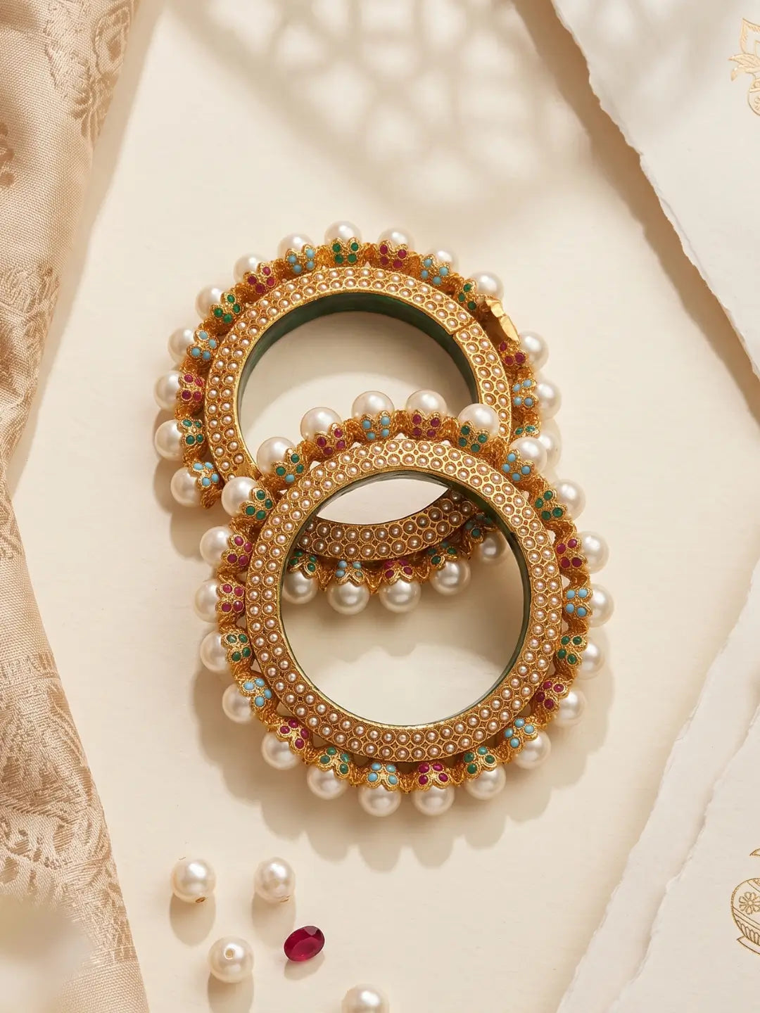 Multicolour Jadau Pearl Pacheli bangles with pink, green and blue stone accents, pearl-style details and a gold-tone base for ethnic looks.