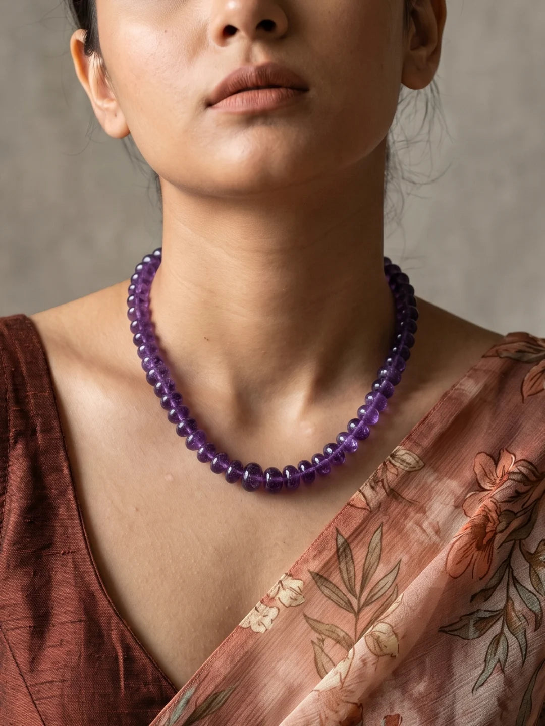 Full view of a long purple amethyst beaded necklace made of a continuous strand of polished natural amethyst beads with gold-plated detailing