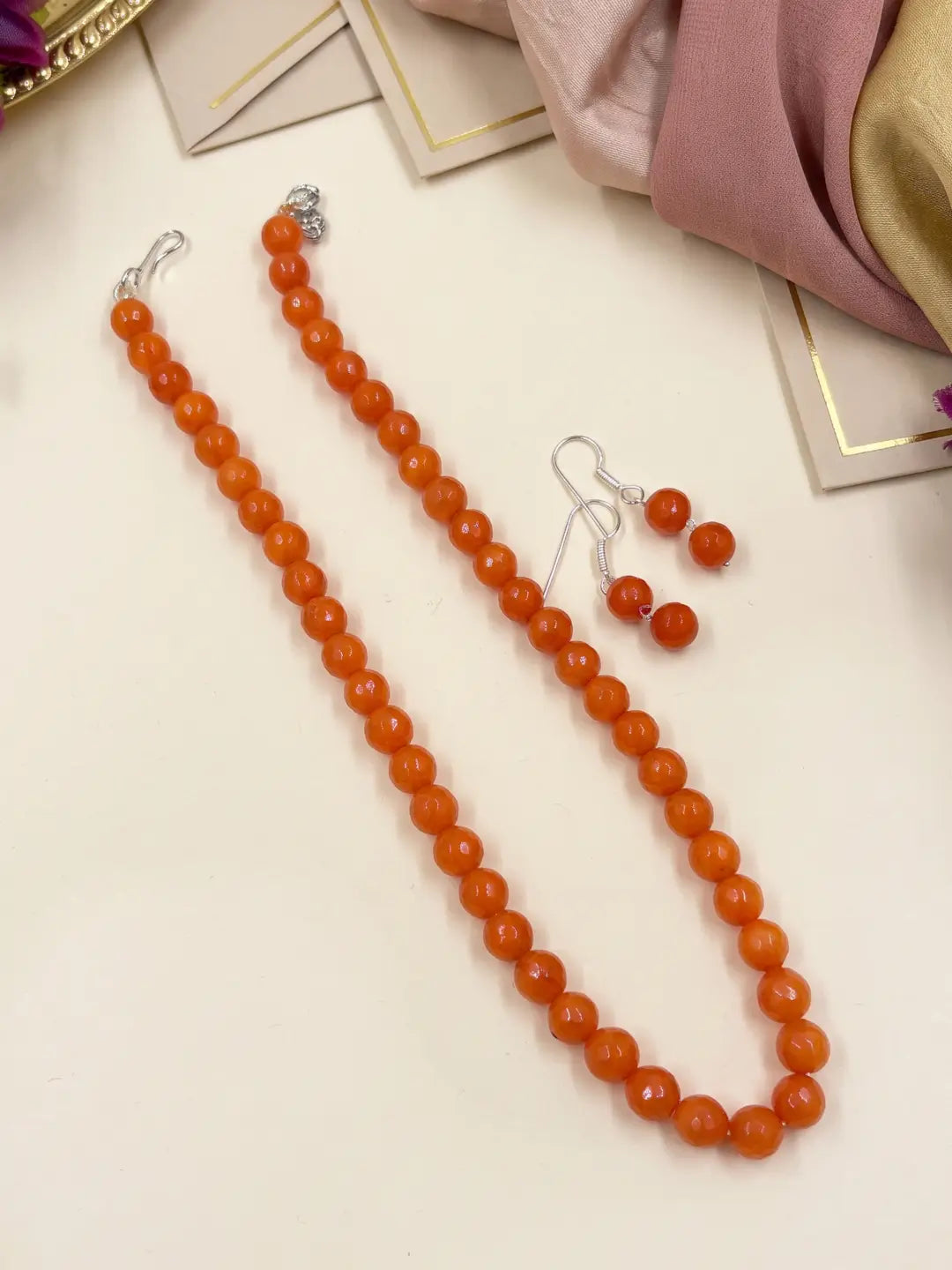 Single-strand orange faceted round jade bead mala necklace shown with matching drop earrings and silver-tone accents