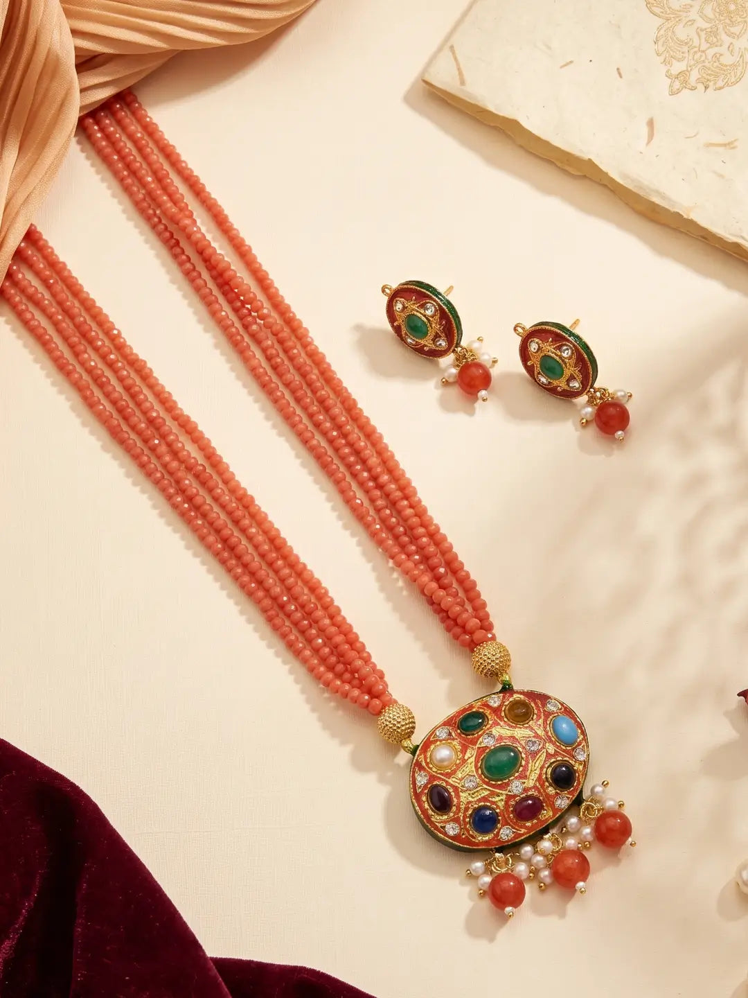 Orange layered bead necklace featuring a Navratna Meenakari pendant and coordinated stud earrings in a traditional style.
