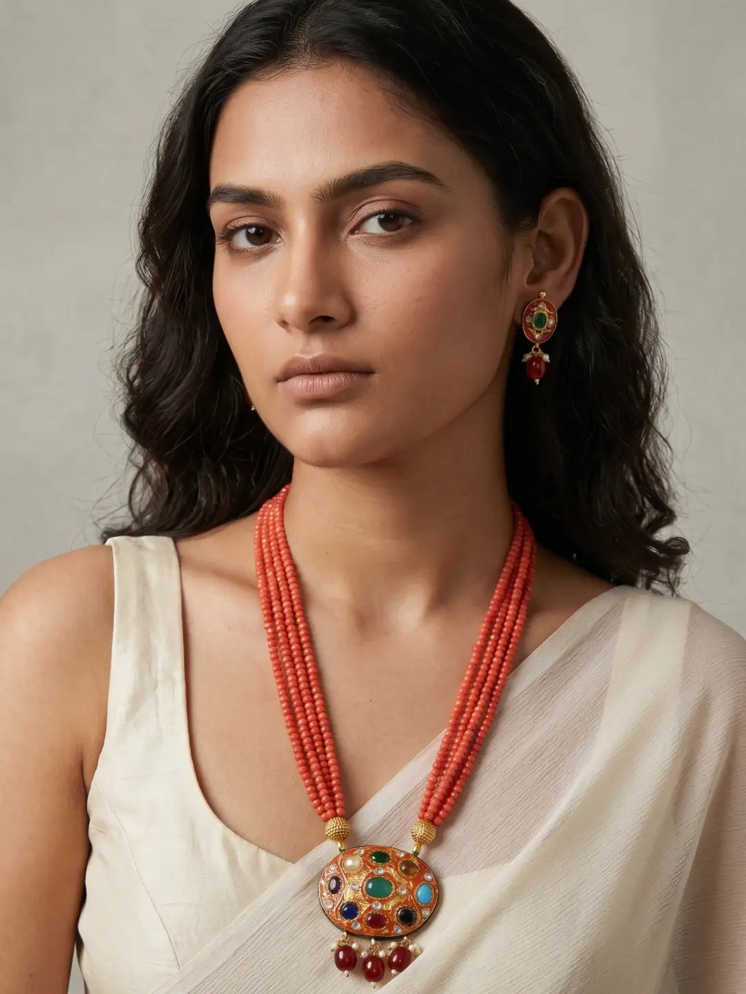 Gold-plated orange necklace set featuring a multicolour Navratna Meenakari pendant, layered bead strands and matching stud earrings.
