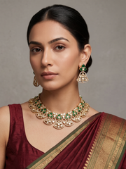 A women is wearing a handcrafted gold-plated floral Kundan necklace set with matching earrings featuring Polki, CZ stones and  ruby red accents, ideal for bridal wear, weddings, festive occasions, and traditional Indian jewellery.