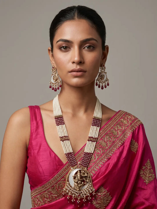 Indian woman wearing a gold-plated red Ganpati temple jewellery set with mother-of-pearl detailing, layered pearl strands and matching statement earrings