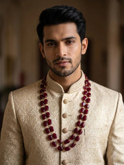Double-strand red jade mala featuring deep red oval beads connected by delicate gold-tone links for a distinguished groom's wedding ensemble.