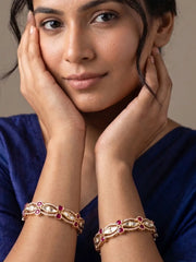 A women wearing a blue saree with gold plated kundan polki and ruby stone bangles on her both wrists 
