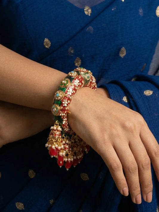 Red Meenakari Kundan kada bangle with jhumka drops, pearl details and stone accents, designed for bridal, wedding and festive outfits.