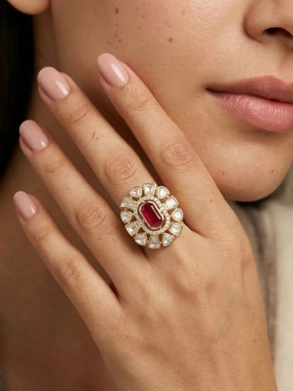 Close-up of a hand wearing an ornate kundan ring with a red gemstone and polki  accents.