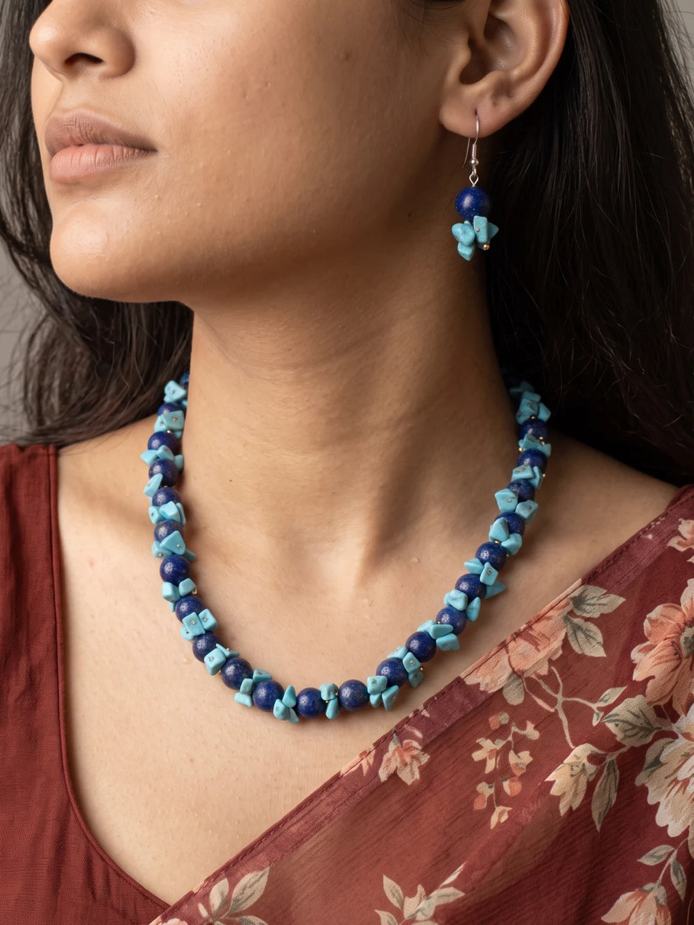 Necklace of round royal-blue lapis lazuli beads with bright turquoise chips and silver-tone spacers, arranged in a curve above a pair of drop earrings
