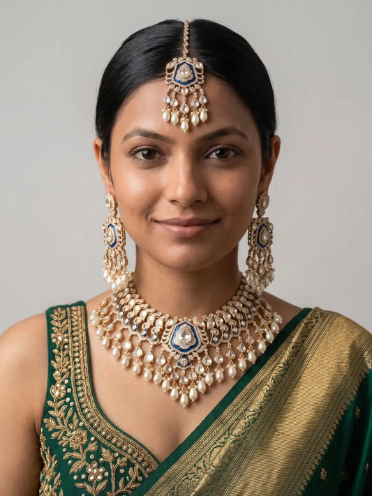 Woman wearing an elaborate royal blue Kundan Polki necklace with cascading pearl drops, matching long earrings and a coordinating maang tikka.