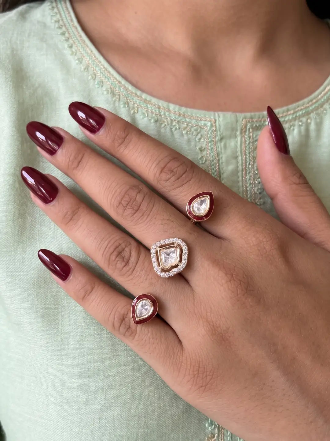 Ruby pink CZ Polki dual finger ring with two connected gold-tone bands, ornate stone elements and enamel detailing for bridal and festive styling