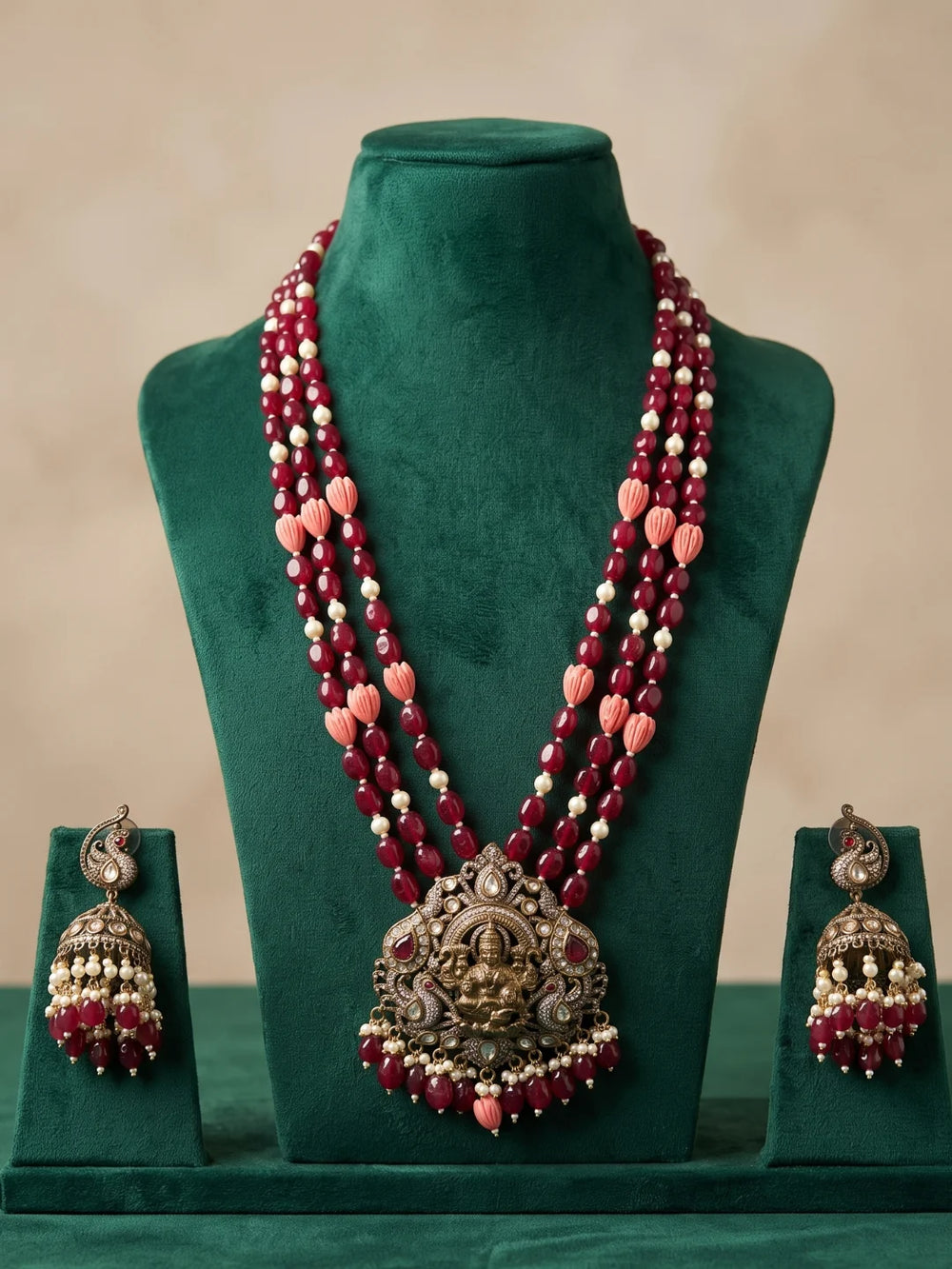 Ruby pink temple jewellery set with an elaborate Lakshmi pendant, decorative stone embellishments, multistrand beads and coordinated jhumka earrings.