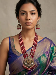 Ruby pink Lakshmi temple necklace featuring an ornate Goddess pendant, antique-style detailing, layered beads and matching jhumka earrings.