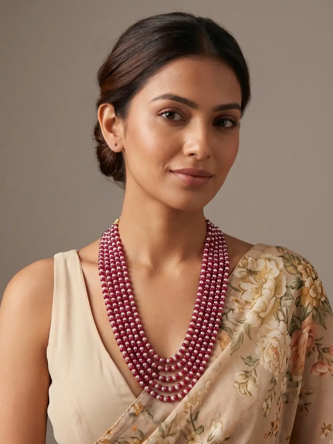 Ruby red jade and natural freshwater pearl layered mala with multiple graduated strands, styled with a saree for an elegant ethnic look.