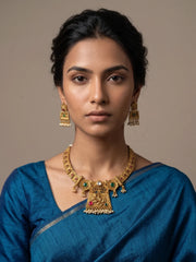 Close view of the short gold plated necklace showing ornate floral motifs, vibrant coloured stones and delicate pearl detailing in antique gold tone