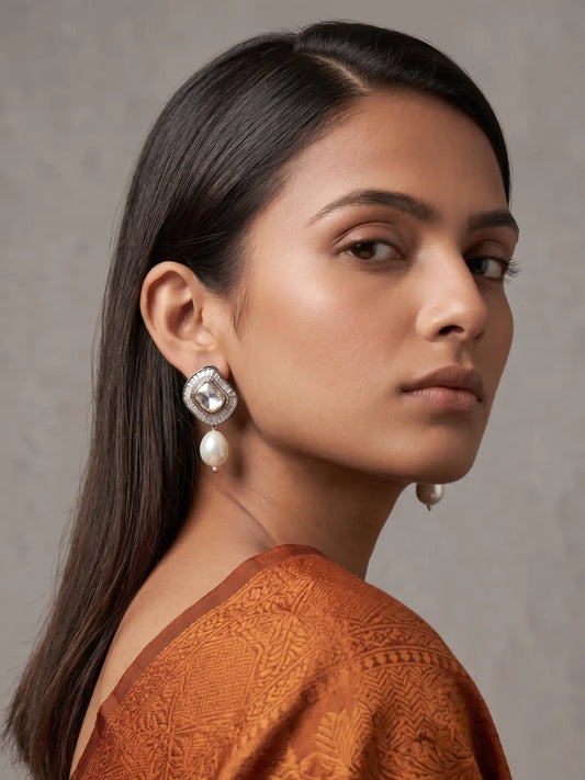 Silver-toned oxidized Kundan studs with brilliant white centre stone, delicate CZ accents and a single lustrous shell pearl drop