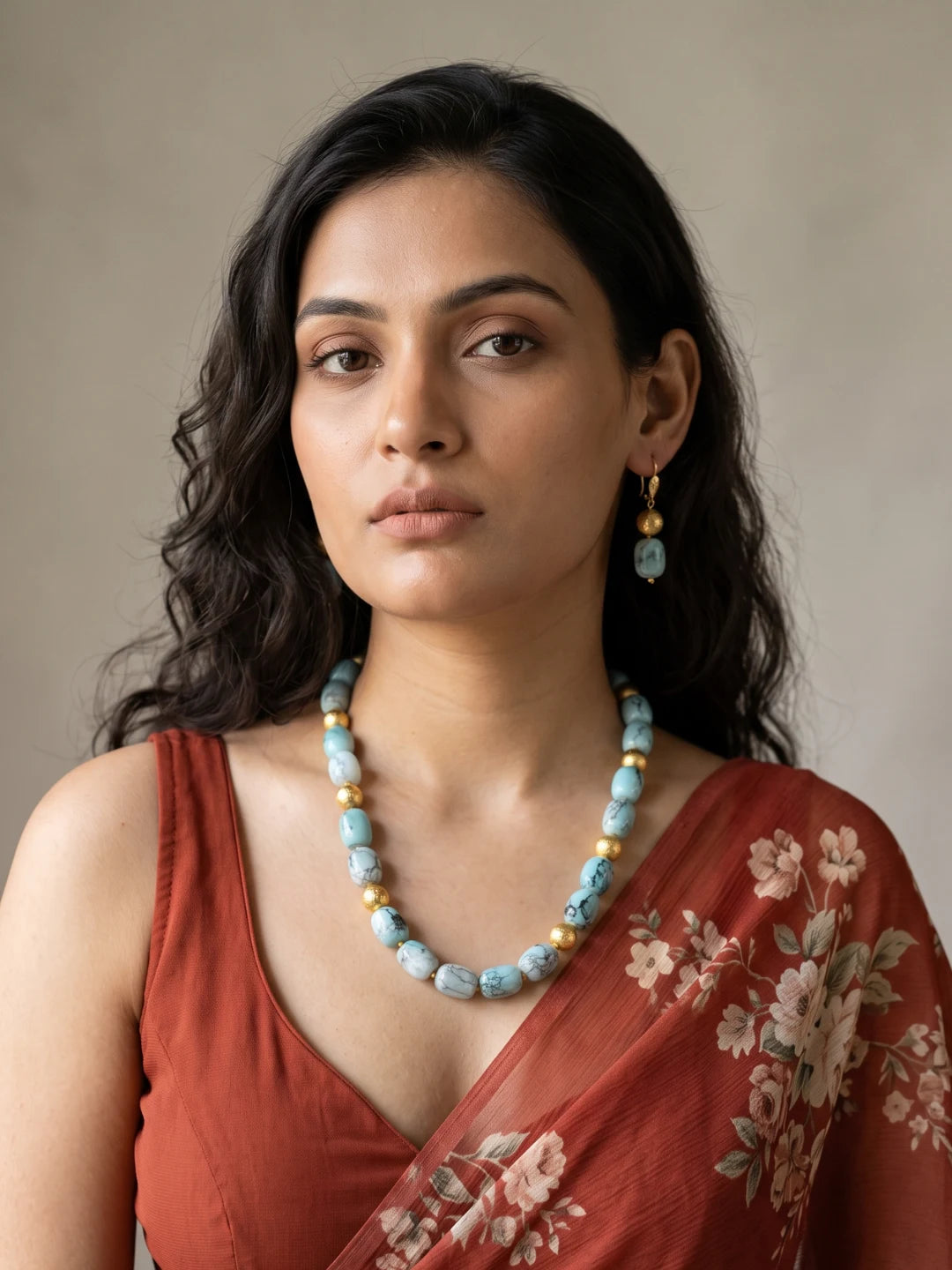Layered necklace of sky blue shaded chalcedony cylinder beads with gold-plated spacers, laid out in a curve beside a pair of matching drop earrings