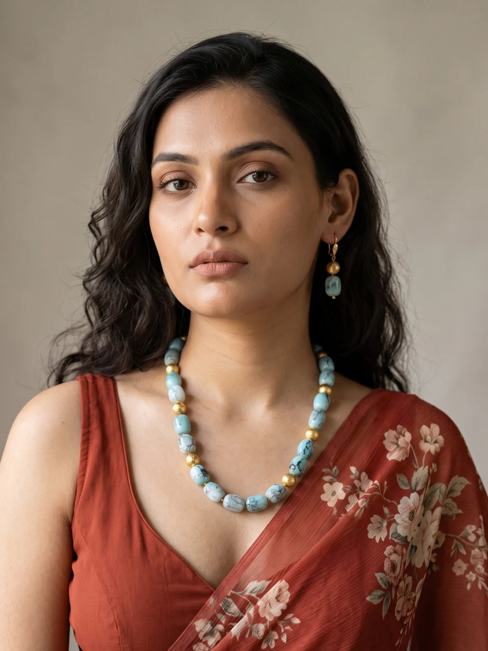 Layered necklace of sky blue shaded chalcedony cylinder beads with gold-plated spacers, laid out in a curve beside a pair of matching drop earrings