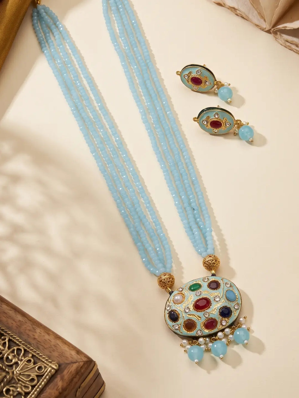 Sky blue layered bead necklace with a decorative multicolour Navratna pendant and matching stud earrings.