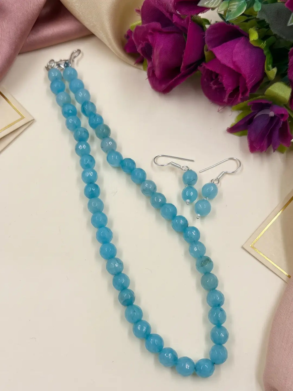 Single-strand sky blue faceted round jade bead mala necklace shown with matching drop earrings and silver-tone accents