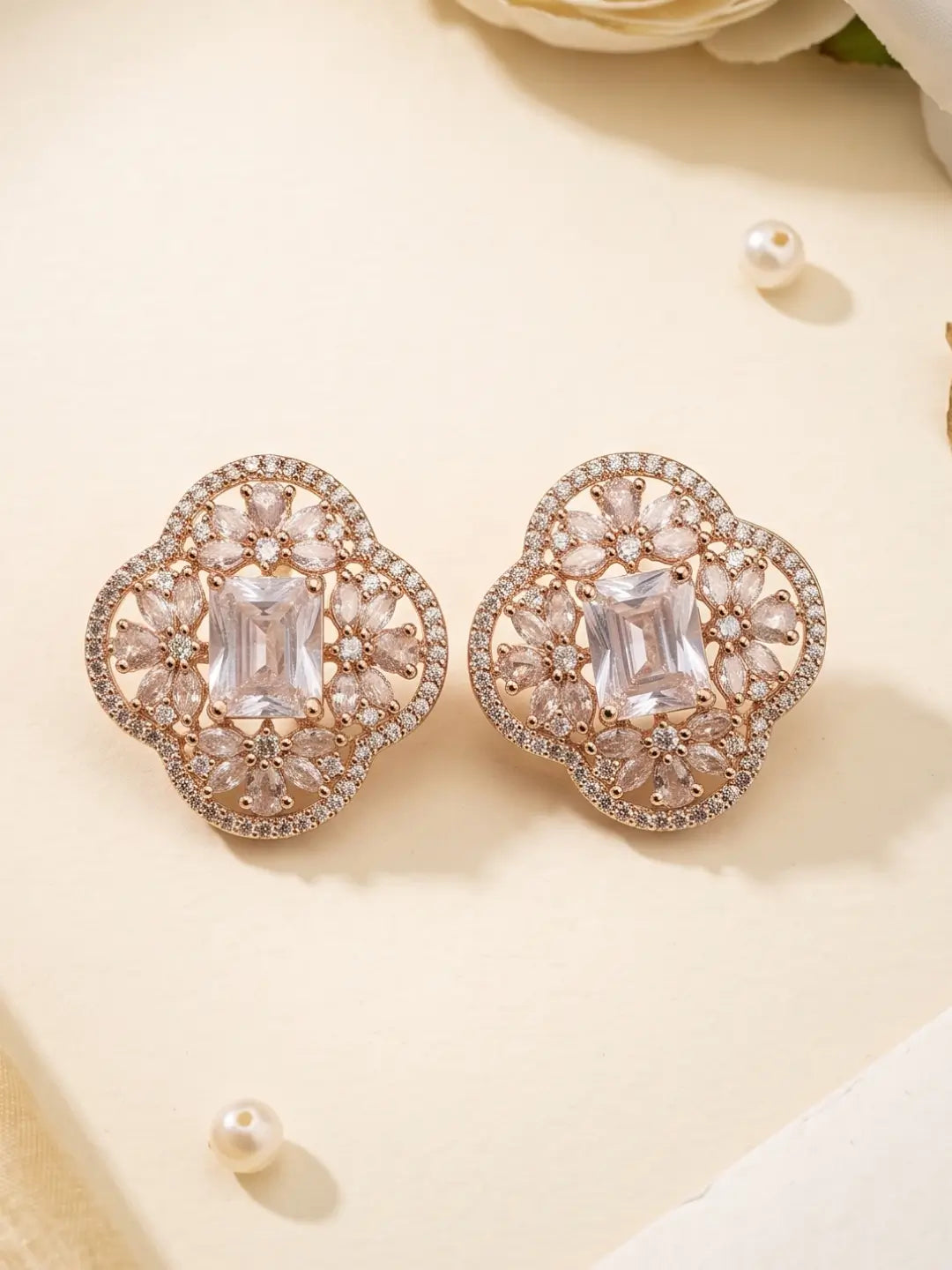 Gold-tone floral stud earrings with a rectangular zircon centre and smaller zircon accents, suitable for sarees, lehengas, kurta sets and Indo-Western looks.