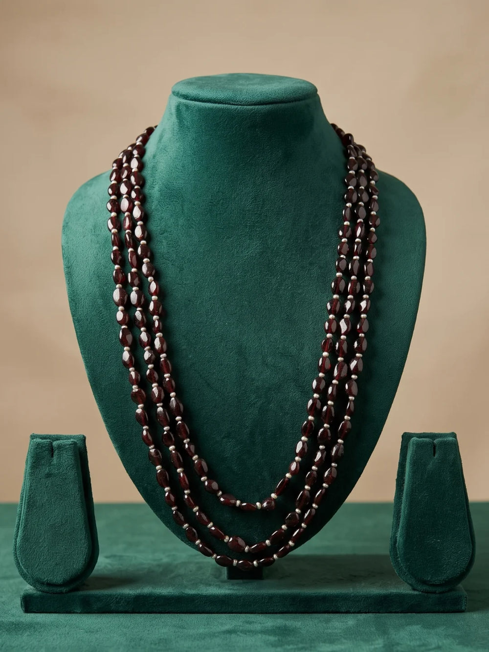 Three-layer dulha necklace combining polished oval garnet beads with freshwater pearls for a traditional groom's sherwani ensemble.