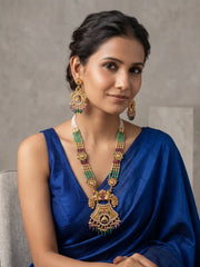 Close-up of the ornate antique gold necklace pendant featuring traditional floral detailing, sparkling Kundan and CZ stones, and dangling green and maroon beads.