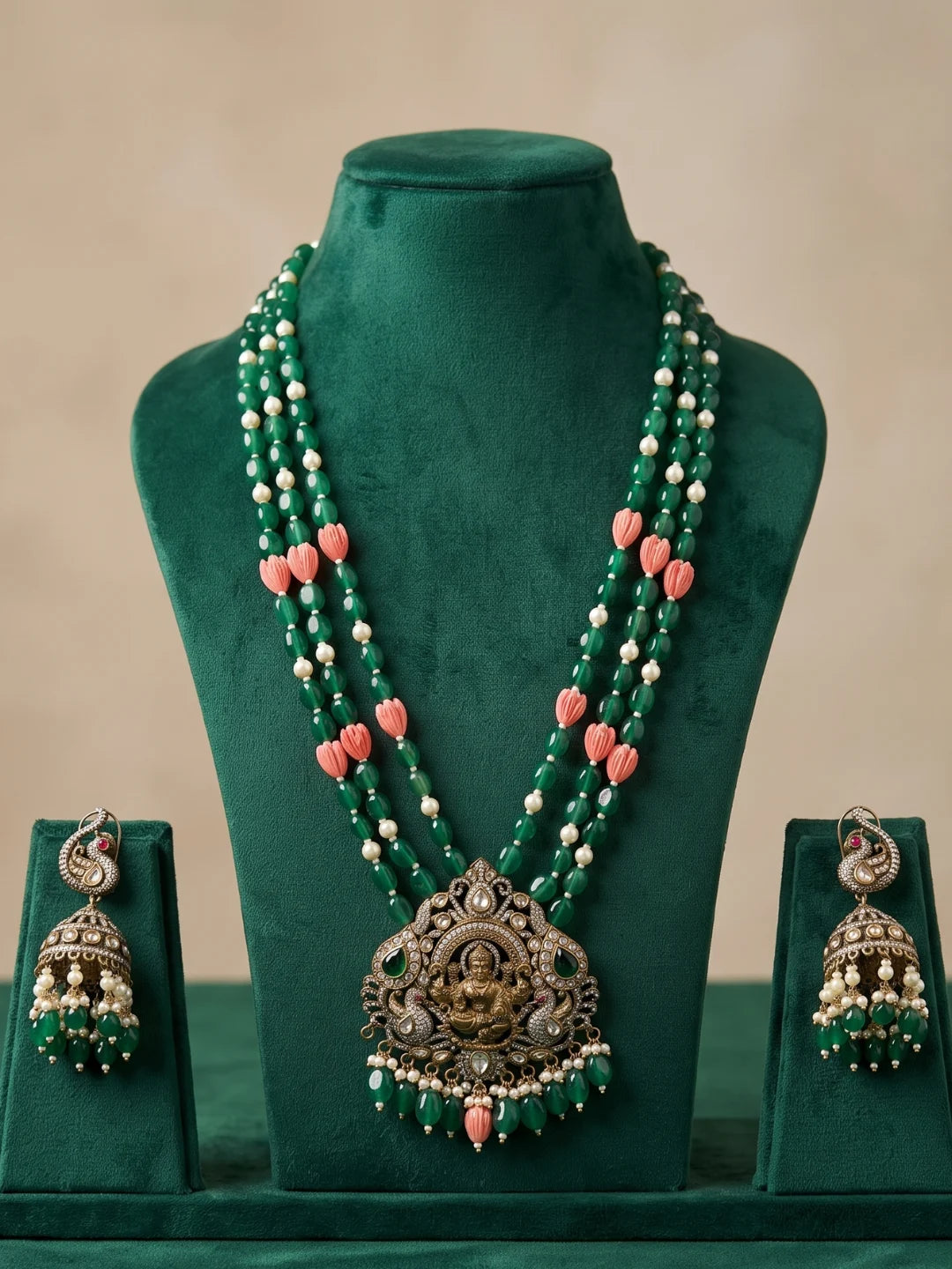 Green temple jewellery set with a decorative Lakshmi pendant, intricate stone embellishments, layered beadwork and coordinated jhumka earrings.