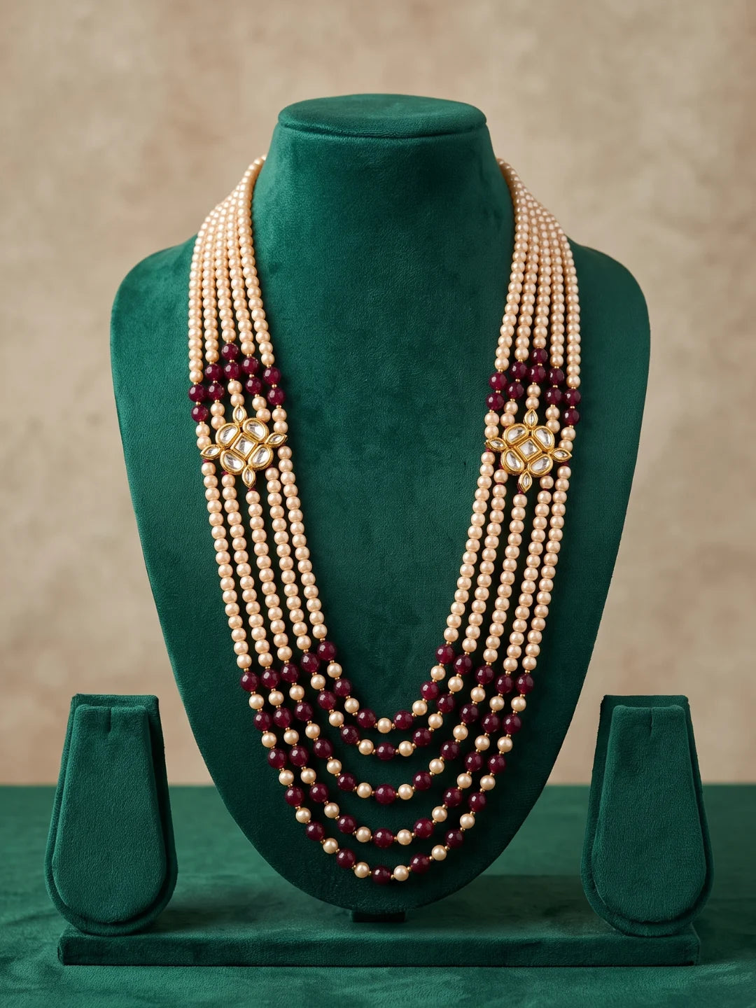Maroon wedding mala for men with multiple bead strands, pearl accents and ornate Kundan-style brooches arranged in a cascading design.
