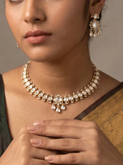 The white Polki choker necklace set features oval floral motifs, clear CZ and imitation stones, a bold centrepiece, and matching dangler earrings.