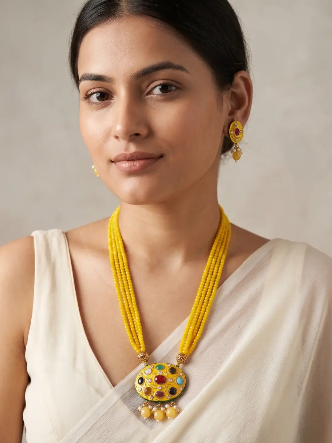 Gold-plated yellow necklace set featuring a Navratna Meenakari pendant, layered beads, pearl accents and matching stud earrings.