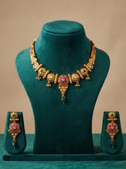 Gold-toned traditional jewelry set displayed on a dark teal velvet mannequin bust, including a necklace with a central pink stone and matching drop earrings on display stands.