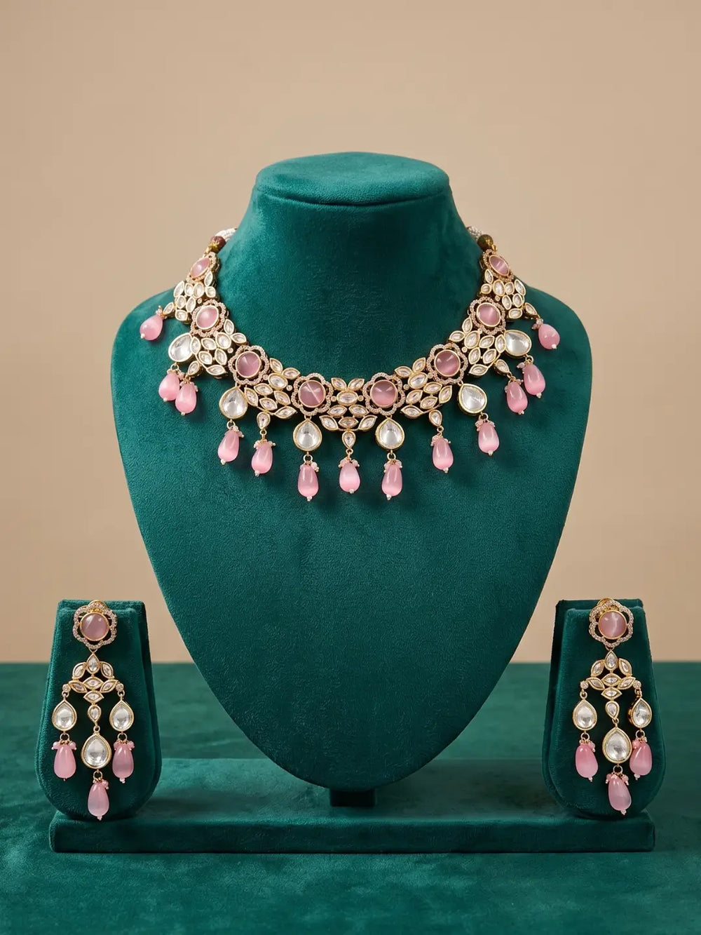 traditional gold plated pink kundan necklace set with pink beaded drops on a green velvet mannequin.