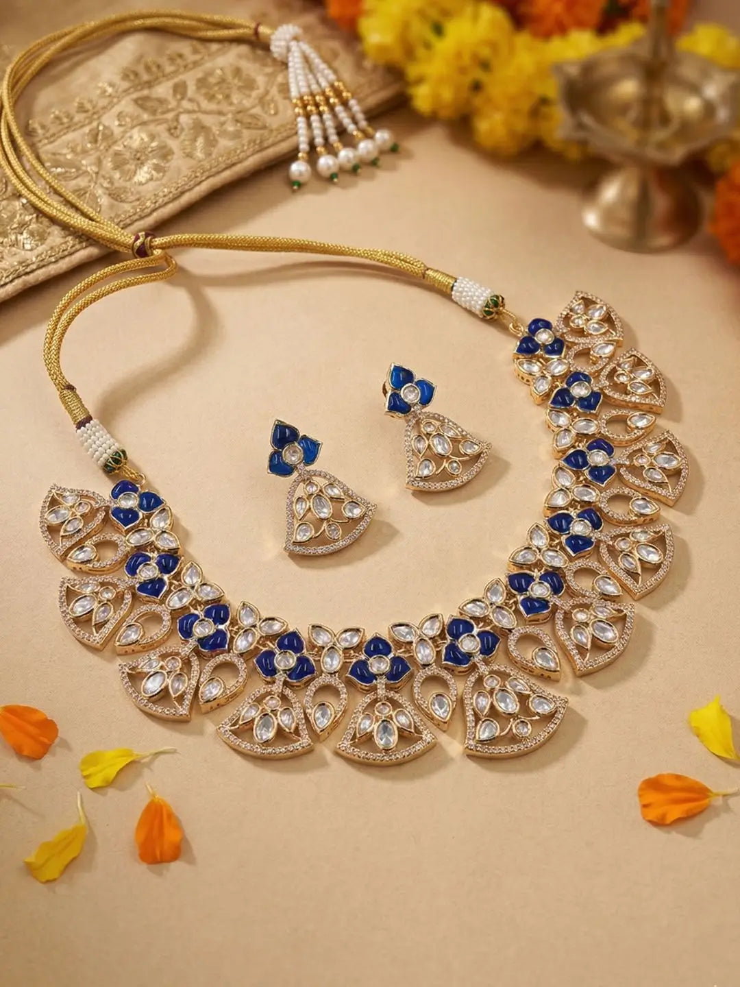 A women is wearing a handcrafted gold-plated floral Kundan necklace set with matching earrings featuring Polki, CZ stones and  royal blue accents, ideal for bridal wear, weddings, festive occasions, and traditional Indian jewellery.