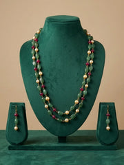 A two-piece jewelry set featuring a multi-strand necklace and matching drop earrings, displayed on a dark green velvet mannequin bust. The necklace features green jade-like beads, cream-colored pearl-like beads, and small red gemstone accents.