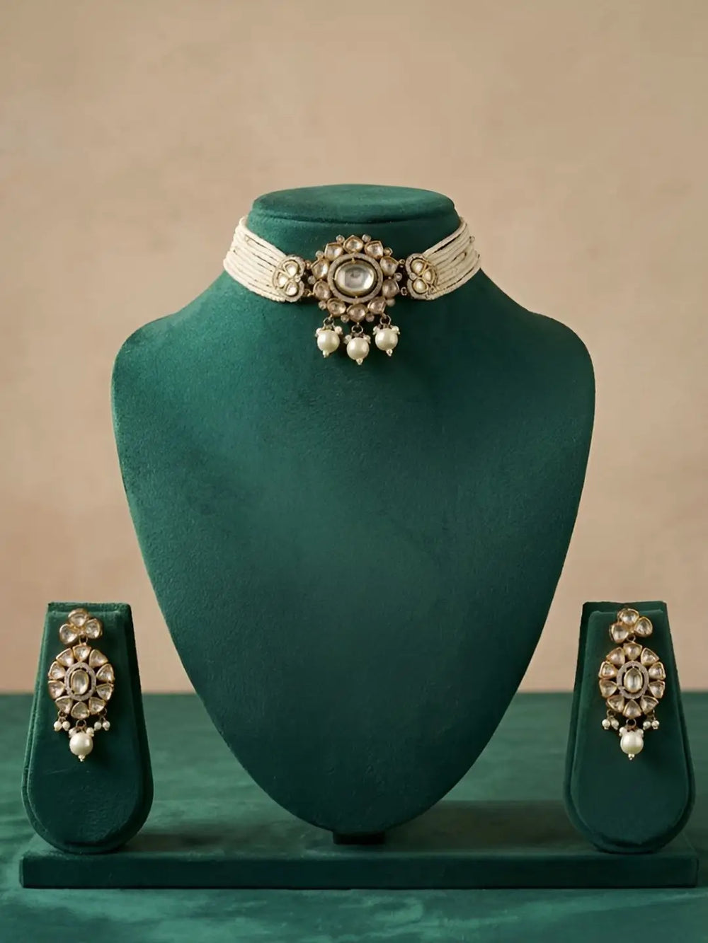 Choker jewelry set with necklace and earrings on a green velvet stand against a beige background