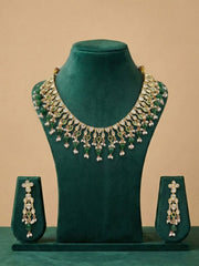 Ornate emerald gren polki kundan necklace set on a green velvet stand with a beige background