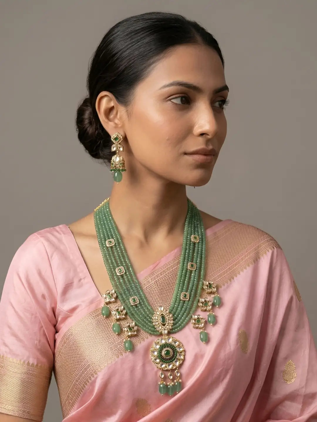 a women in a pink saree wearing Handcrafted emerald green multi-layer beaded long necklace featuring an elegant Kundan pendant with matching earrings, perfect for bridal wear, weddings, festive celebrations, and traditional Indian jewellery.