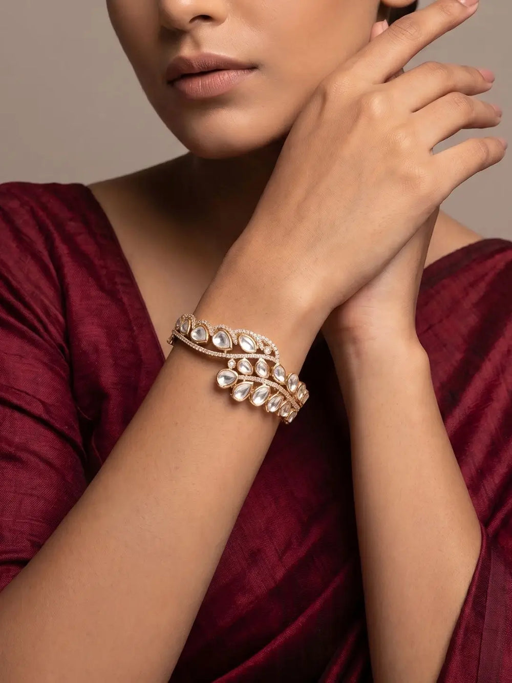 A woman wearing a kundan polki kada  bracelet with a neutral background