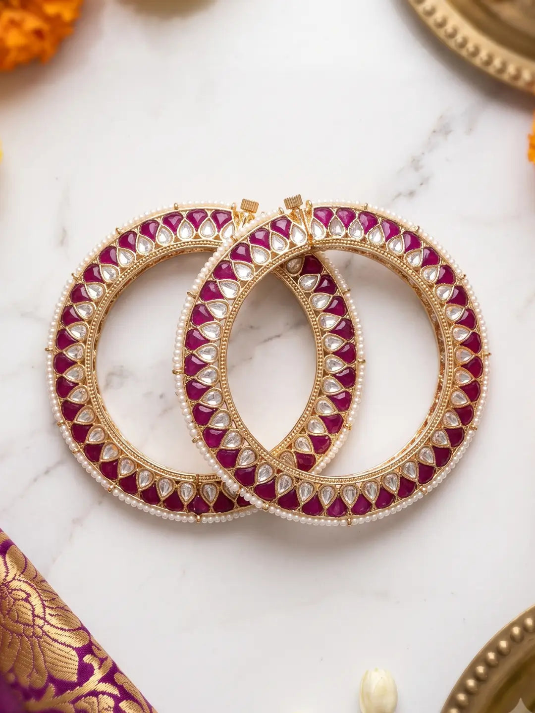 Handcrafted gold-plated Kundan bangles featuring sparkling Kundan stones, elegant pearl borders, and ruby red enamel detailing, perfect for bridal wear, weddings, festive occasions, and traditional Indian jewellery.