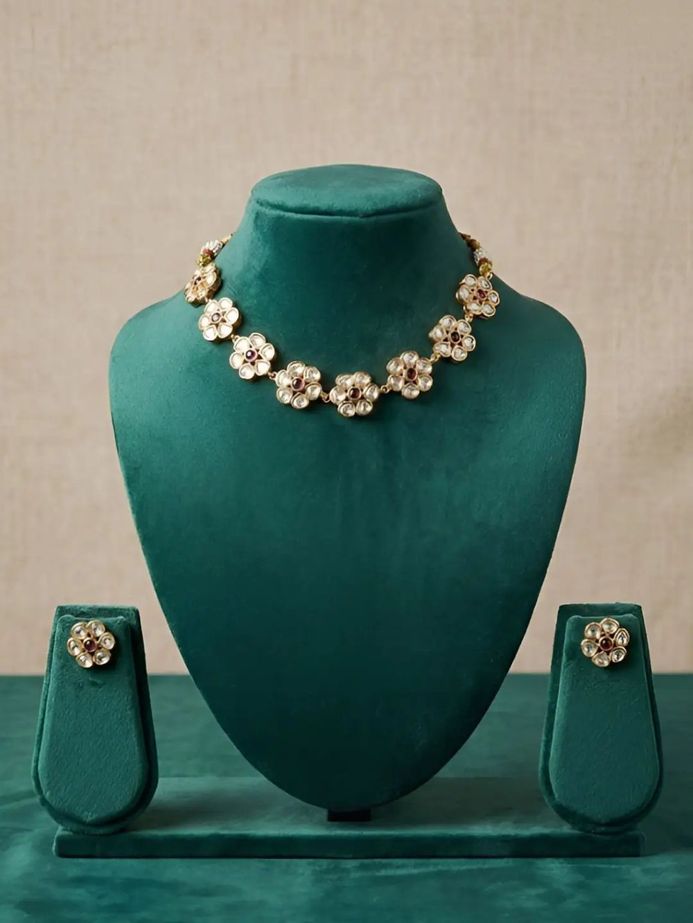 Polki necklace and earrings set on a green velvet mannequin against a beige background