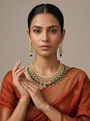 a women wearing a designer Gold Plated Emerald Green Polki Kundan Necklace & Earring Set With Green Bead Drops on a red saree