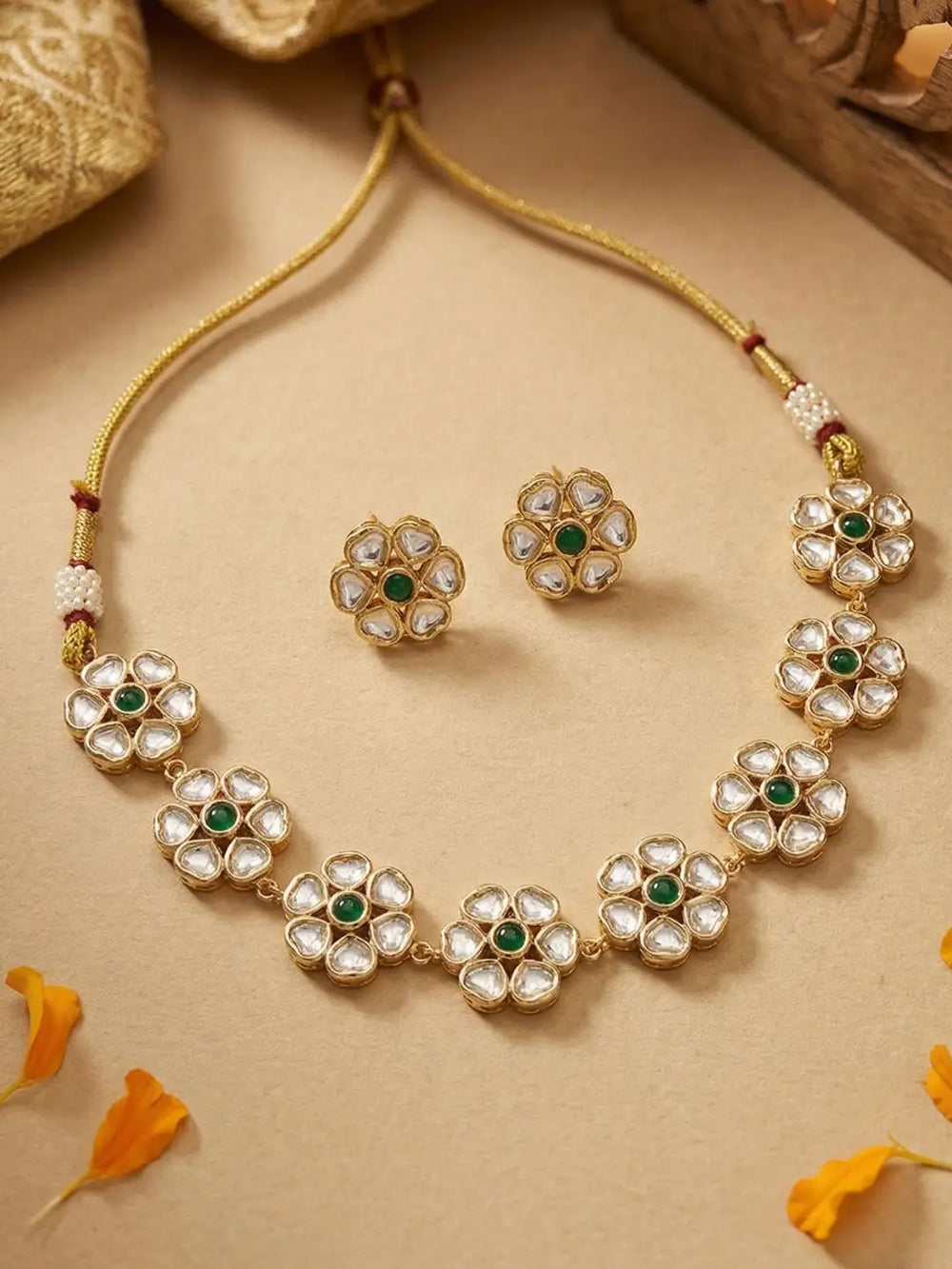 Gold-plated flower-design polki necklace and earrings on a beige background