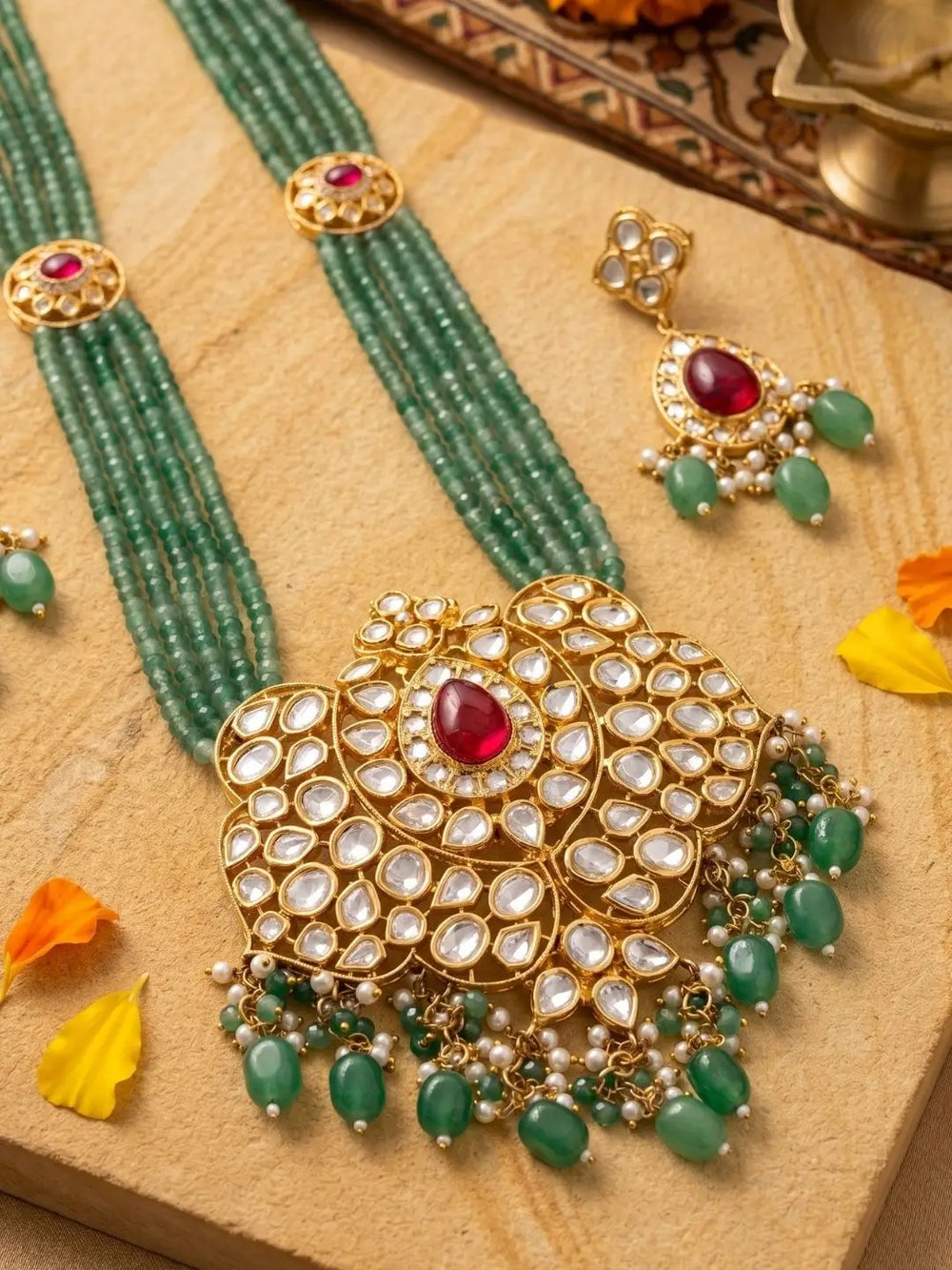 Full view of a layered multi-strand green jade bead necklace with kundan brooches and a large central pendant resting at the neckline
