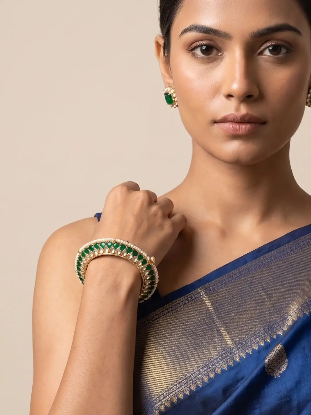 a women wearing a Handcrafted gold-plated Kundan bangles featuring sparkling Kundan stones, elegant pearl borders, and emerald green enamel detailing, perfect for bridal wear, weddings, festive occasions, and traditional Indian jewellery.