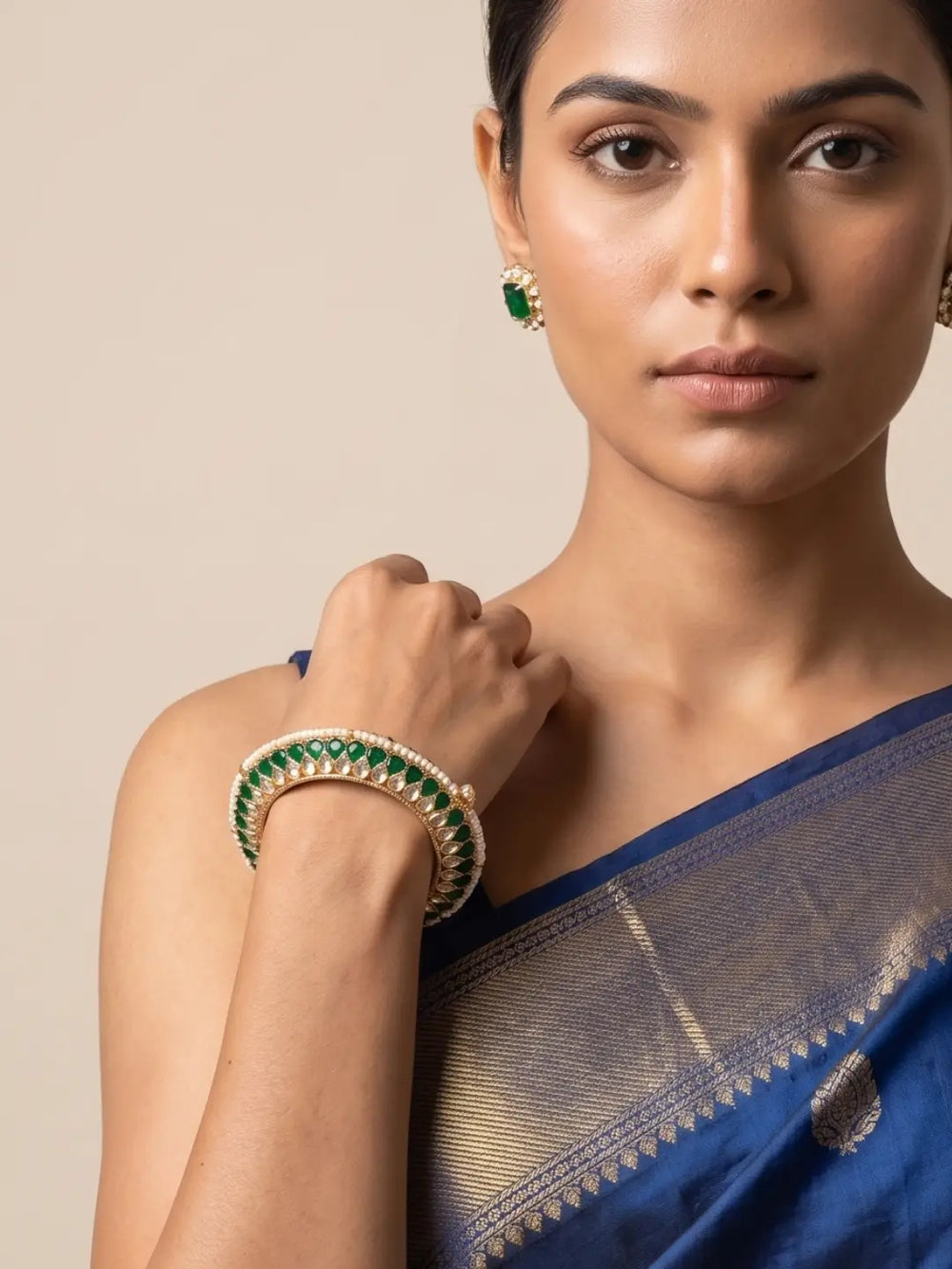 a women wearing a Handcrafted gold-plated Kundan bangles featuring sparkling Kundan stones, elegant pearl borders, and emerald green enamel detailing, perfect for bridal wear, weddings, festive occasions, and traditional Indian jewellery.