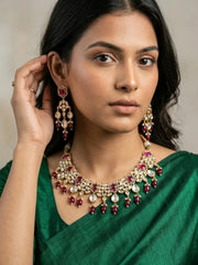 a women in a green saree wearing an Elegant Ruby pink Kundan necklace set with matching chandelier earrings featuring premium Kundan stones, red bead drops, and gold-tone finish, perfect for bridal wear, weddings, festive occasions, and traditional Indian jewellery.