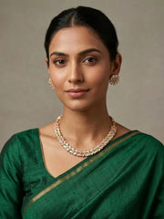 A woman wearing a Gold Plated green Kundan Necklace And Earring Set on a green saree | Festive And Wedding Wear Jewellery