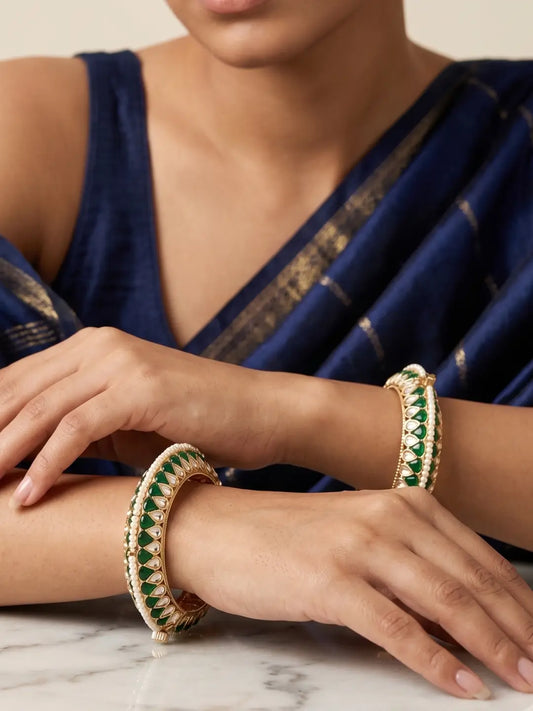 a close up portrait of a women wearing Handcrafted gold-plated Kundan bangles featuring sparkling Kundan stones, elegant pearl borders, and emerald green enamel detailing, perfect for bridal wear, weddings, festive occasions, and traditional Indian jewellery.