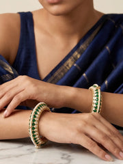 a close up portrait of a women wearing Handcrafted gold-plated Kundan bangles featuring sparkling Kundan stones, elegant pearl borders, and emerald green enamel detailing, perfect for bridal wear, weddings, festive occasions, and traditional Indian jewellery.